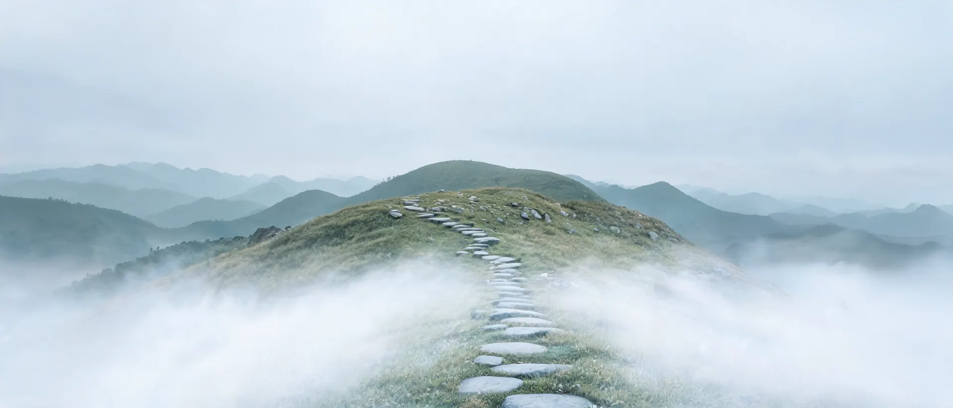 A stone path climbing a misty ridge